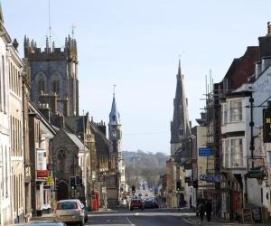 uma rua da cidade com uma torre de relógio e uma igreja em The Casterbridge em Dorchester