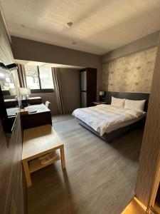 a bedroom with a large bed and a desk and a bed sidx sidx sidx sidx at DLInn Hotel in Taichung