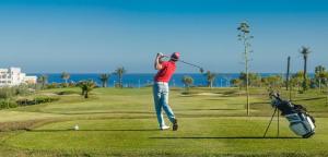 a man swinging a golf club on a golf course at Apartamento playa y golf I Retamar in Retamar