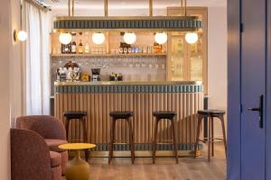 un bar con tres taburetes y un mostrador en una habitación en Bijou Hôtel Paris Boulogne, en Boulogne-Billancourt