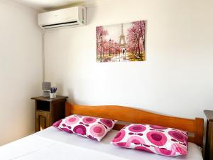 a bedroom with a bed with pink pillows and a painting at Hilja's Oliven Garden Bungalows in Ulcinj +107 photos