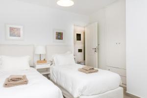 two beds in a white room with towels on them at Naxian Resort in Aliko Beach