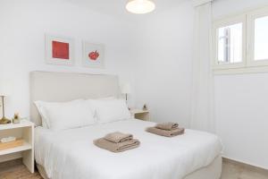 Un dormitorio blanco con una cama blanca con toallas. en Naxian Resort, en Aliko Beach