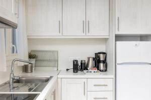 una cocina con armarios blancos y fregadero en Naxian Resort, en Aliko Beach