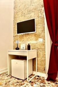 einen weißen Schreibtisch mit einem TV an einer Steinmauer in der Unterkunft Bethel come Casa Apartments in Neapel