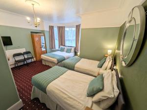 a hotel room with two beds and a mirror at The George Guest House in Plymouth