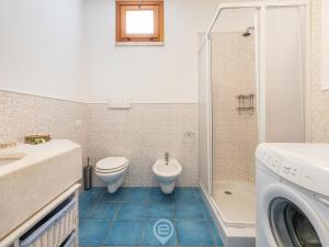 a bathroom with a toilet sink and a washing machine at Casa Ariel - Chia Beach in Chia