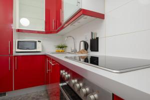 una cucina con armadi rossi e forno a microonde di Bukowińska Apartments with Balcony and Parking and Swimming Pool by Renters a Varsavia