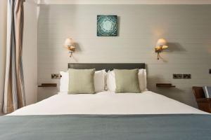 um quarto com uma grande cama branca e 2 candeeiros em Port William Inn em Tintagel