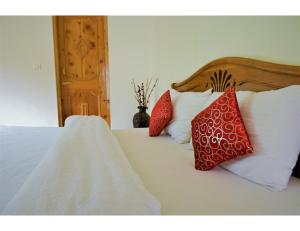 a bedroom with a bed with red and white pillows at Acharya Cottage, Manali in Manāli