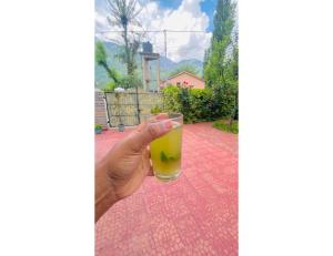 a hand holding a glass of orange juice at Acharya Cottage, Manali in Manāli