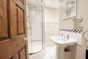 a white bathroom with a shower and a sink at Jenny Wren Cottage in Middleham +19 photos