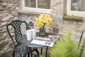 a table with a vase of yellow flowers on it at Jenny Wren Cottage in Middleham