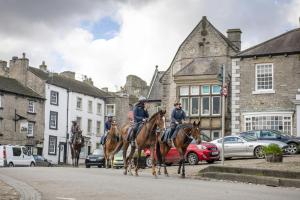 three police officers riding horses down a city street at Jenny Wren Cottage in Middleham