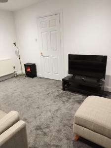 sala de estar con TV y chimenea en M Rooms - entire 1 bedroom, furnished pub flat, en Kirk of Shotts