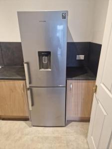 a stainless steel refrigerator in a small kitchen at M Rooms - entire 1 bedroom, furnished pub flat in Kirk of Shotts