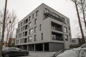 a large brick building with cars parked in a parking lot at Charming Apartment In Zeimena's Street in Kaunas