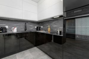 a kitchen with black cabinets and a microwave at Modern Apartment Close to the Beach in Gdańsk by Noclegi Renters in Gdańsk