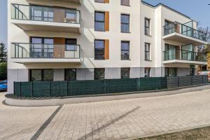 a white building with a green fence in front of it at Modern Apartment Close to the Beach in Gdańsk by Noclegi Renters in Gdańsk