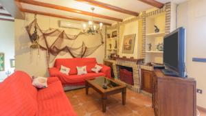 ein Wohnzimmer mit einem roten Sofa und einem TV in der Unterkunft Casa La Marquesa Punta Umbria by Ruralidays in Punta Umbría