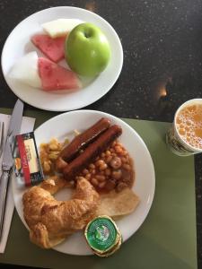 two plates of food with sausage beans and fruit at Charming Rooftop Apartments with Great view & Free Strong Wi-Fi - 40percent Long-stay Disc- Red Lotus Oasis in Accra