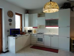 una cocina con armarios blancos y un ordenador en la encimera en Ferienwohnung mit Balkon mit Meerblick und Autostellplatz, en Mascali