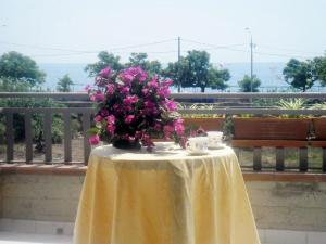 una mesa con un jarrón con flores rosas. en Ferienwohnung mit Balkon mit Meerblick und Autostellplatz, en Mascali