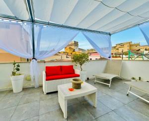 ein Wohnzimmer mit einem roten Sofa auf dem Balkon in der Unterkunft Meetup on The Terrace View With private parking in Palermo