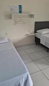 1 dormitorio con 2 camas y suelo de baldosa blanca en Suítes na Barra da Lagoa, en Florianópolis