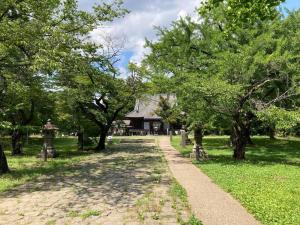 a path in a park with trees and a building at Roopt仙台薬師堂 in Sendai