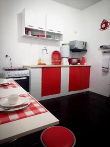 een keuken met rode en witte kasten en een tafel bij Casa ampla, arejada, muitos jogos e quarto cinema! in Rio das Ostras