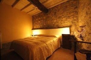 ein Schlafzimmer mit einem Bett und einer Steinmauer in der Unterkunft Ferienwohnung für 2 Personen  2 Kinder ca 35 m in Castè, Italienische Riviera Golf von La Spezia in Quaratica