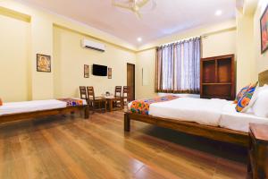a bedroom with two beds and a table and chairs at GMI Hotel and Benquet Jaipur in Jaipur