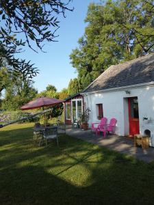 Casa con sillas rosas, mesa y sombrilla en Clooncerna Cottage, en Gort