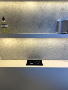 two shelves with a bottle of soap and a scale at Suite Haspengouw in Sint-Truiden