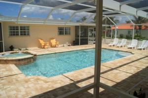 a large swimming pool with chairs and a patio at Beach Resort in Cape Coral in Cape Coral