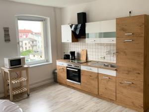 een keuken met houten kasten, een wastafel en een raam bij Citywohnung mit Gartenzugang in Schwerin