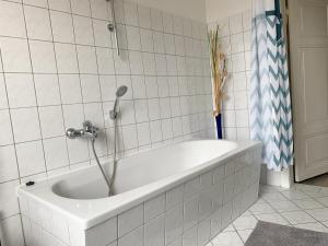 een wit bad met een douche in de badkamer bij Citywohnung mit Gartenzugang in Schwerin