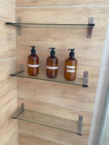 three bottles of soap sitting on shelves on a wall at Alexandra's View in Piraeus
