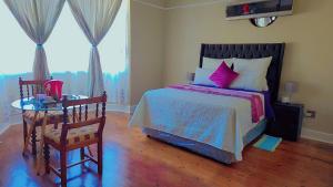 1 dormitorio con 1 cama y 1 mesa con silla en DreamWest Living The Guesthouse, en Krugersdorp