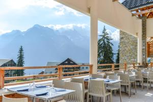 a restaurant with tables and chairs on a balcony at Villages Clubs du Soleil - OZ EN OISANS in Oz