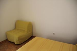 a yellow chair sitting next to a bed in a room at Ferienwohnung in Novigrad mit privatem Parkplatz in Karpinjan +4 photos