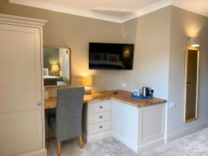 Zimmer mit einem Schreibtisch und einem TV an der Wand in der Unterkunft Caley Hall in Hunstanton