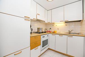 una cocina blanca con armarios y electrodomésticos blancos en CaLuisel en Tenno
