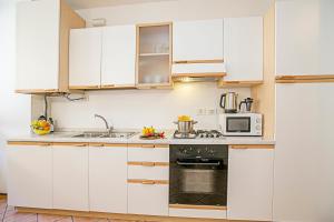 eine Küche mit weißen Schränken und einer Mikrowelle in der Unterkunft Appartamento Centro Storico Riva 2 - Happy Rentals in Riva del Garda