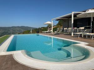 una piscina de agua azul frente a una casa en Ca' Nobili - Charming Country House en Vetto