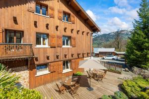 a building with a deck with tables and an umbrella at Smartstay au reve Savoyard 5 in Morillon