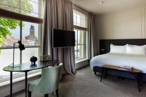 Cette chambre comprend un lit, un bureau et une fenêtre. dans l'établissement Pillows Luxury Boutique Hotel aan de IJssel, à Deventer