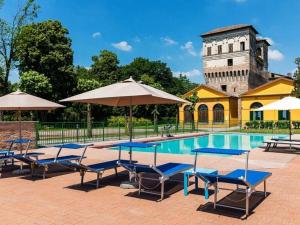 une piscine avec des chaises et des parasols et un bâtiment dans l'établissement Palazzo Barbò Modern retreat, à Pumenengo
