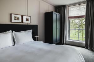 a bedroom with a large white bed and a window at Pillows Luxury Boutique Hotel aan de IJssel in Deventer